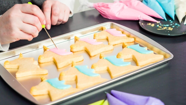 Decorating unicorn sugar cookies with multi-color royal icing.