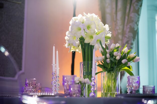 Decoration of a festive dinner with Lily flowers on the wedding table in the interior of the restaurant.Wedding decor.