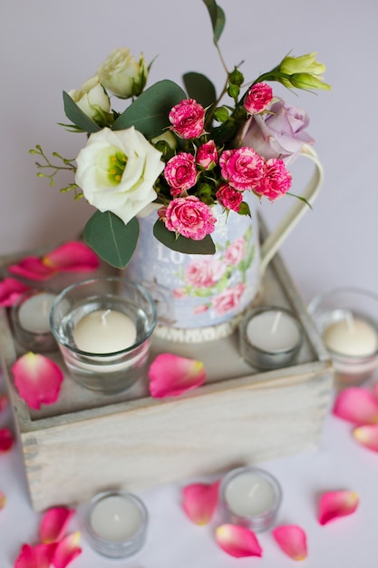 テーブルの上に立っている鉄の花瓶と平らな白いキャンドルの花の装飾