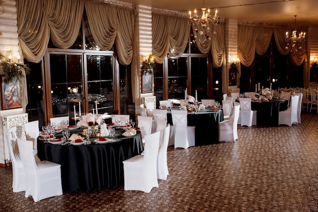 Decoration of tables with burning candles, decor in shades of black, red and white