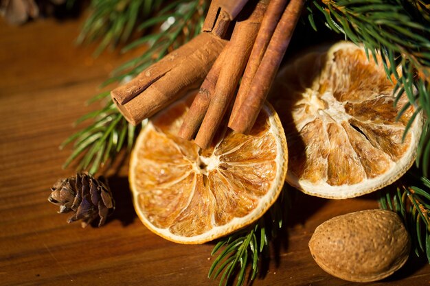 장식, 겨울, 휴일 및 새해 개념 - 나무 테이블에 계피와 말린 오렌지가 있는 크리스마스 전나무 가지를 닫습니다