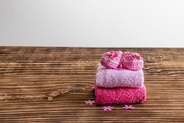 Decoration with pink baby shoe, wooden background, space for text