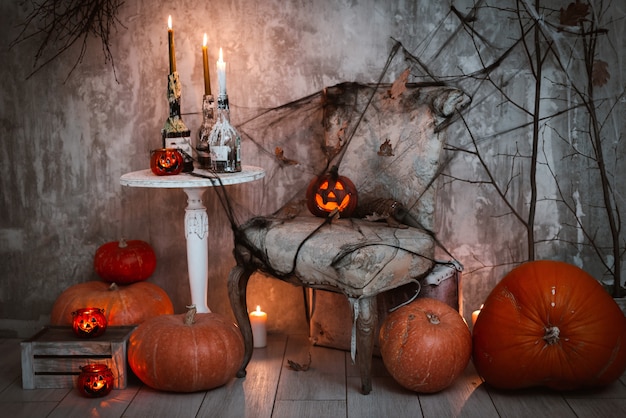 Decorazioni per la festa di halloween. una composizione spaventosa con la zucca di jack e candele accese, ragnatele e la scopa di una strega su un muro di cemento