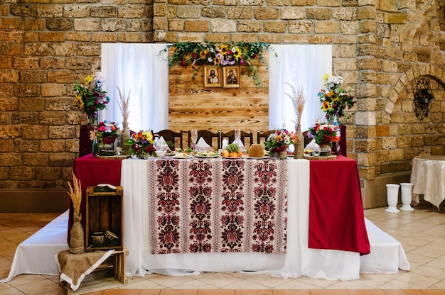 Decorations made of wood and wildflowers served on the festive table setting in rustic style for wedding ceremony.