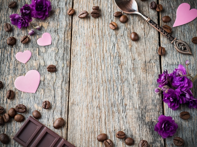 Decorations for Valentines day paper hearts, violets and chocolate coffee on rustic wooden background.