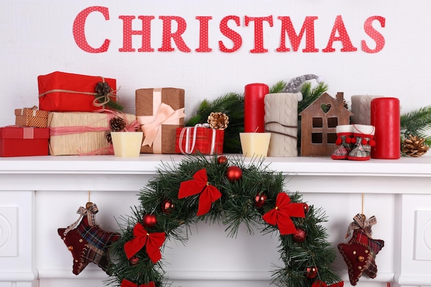 Decorations with Merry Christmas inscription on mantelpiece on white wall background