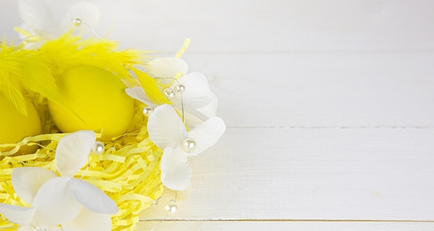 Decorative basket with yellow eggs decorated with feathers in the sun