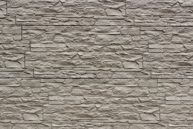 Decorative beige wall of artificial torn stone as a background or texture.