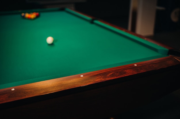 Decorative billiard hole and green table with balls in the billiard club.