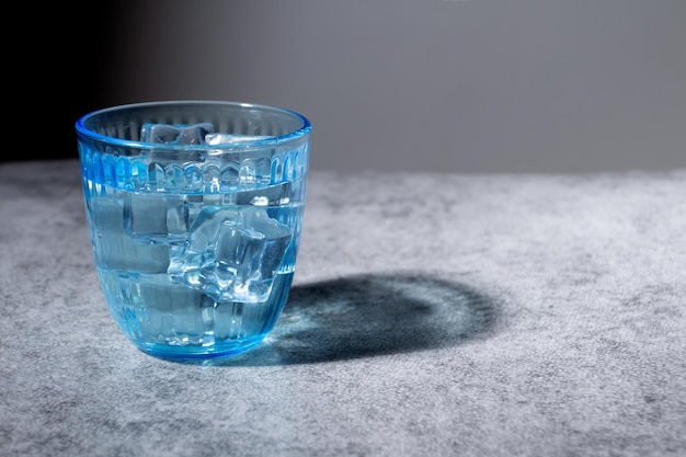 Decorative blue glass with water and ice on rustic surface