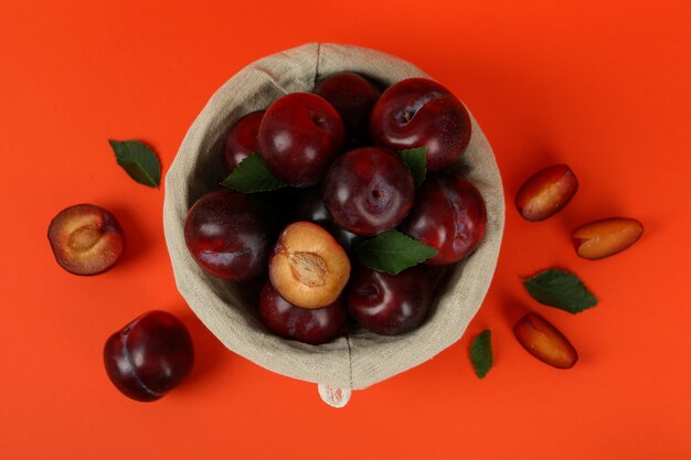 Decorative bowl with plums on an orange background.