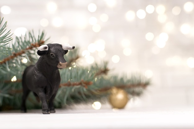 Decorative bull, symbol of the new year on the background of christmas trees and blue bokeh.