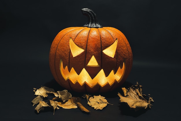 Decorative carved pumpkin with dried leaves for the Halloween