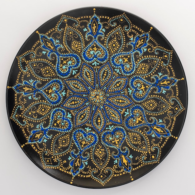 Decorative ceramic plate with black blue and golden colors painted plate on background dot painting