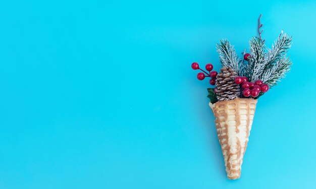 Photo decorative christmas bouquet of christmas tree branch in a waffle cone on blue background creative minimal concept of new year