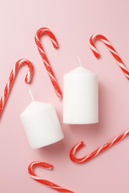 Decorative Christmas composition from candles candy canes isolated on pink background