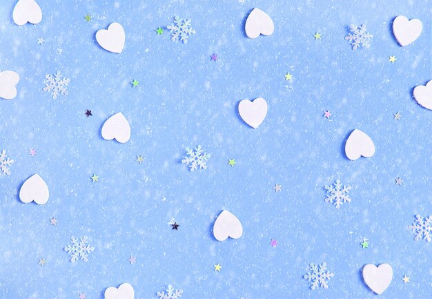 Decorative Christmas and New Year soft blue background with white wooden hearts and snowflakes. Festive template. Greeting card with copy space. Snowfall effect.