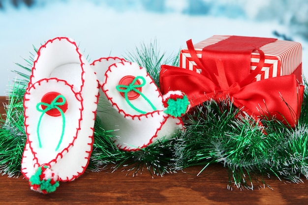 Decorative Christmas shoes with present on table on bright background