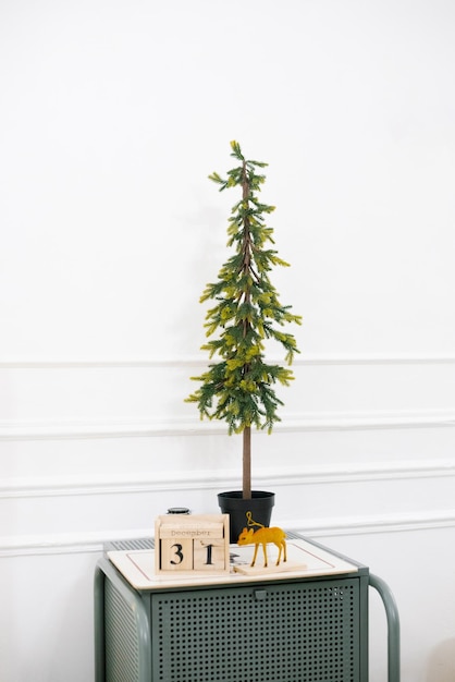 Decorative Christmas tree stands on the bedside table in the bedroom decorated for the New Year