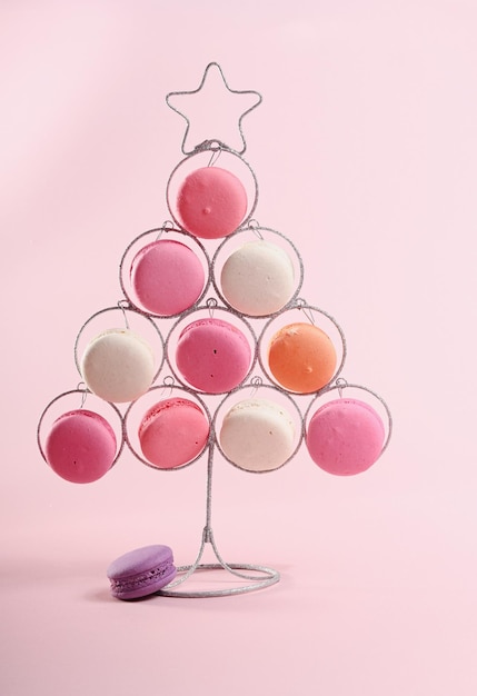 Decorative Christmas tree with sweet macaroons on pink background