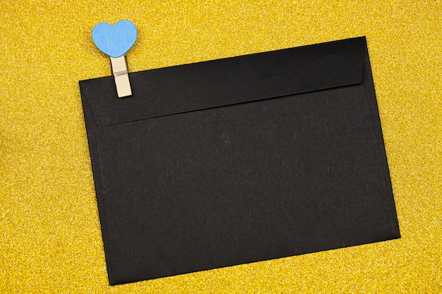 Decorative clothespin with heart and black envelope on yellow surface