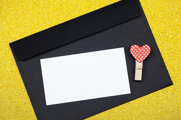 Decorative clothespins with heart and black envelope on yellow surface