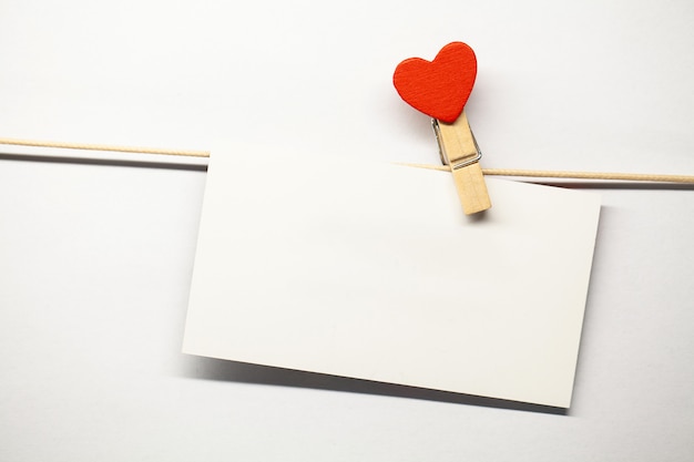decorative clothespins with a heart and blank white greeting card hanging on a rope