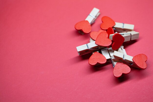 Decorative clothespins with heart on red surface