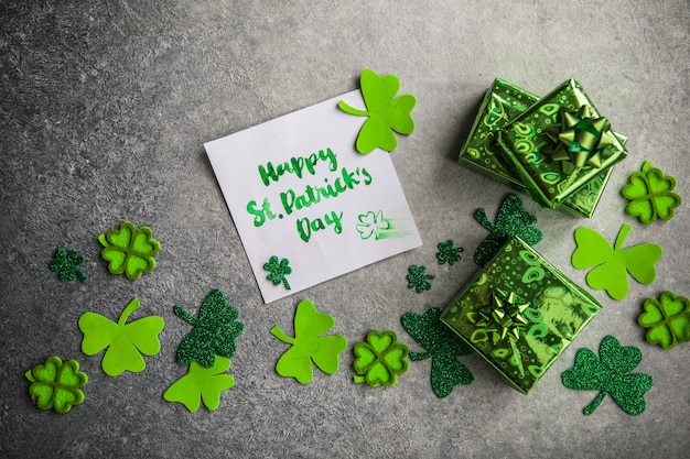 장식 클로버 잎, 녹색 선물 상자, 돌 배경에 동전, 평평하다. 성 패트릭의 날 축하. 카드 해피 성 패트릭의 날