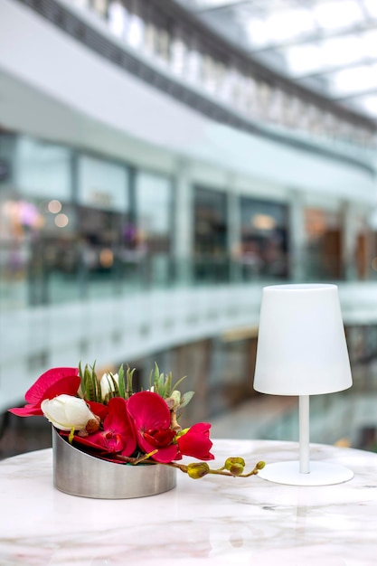 Decorative composition of artificial flowers and white table lamp on marble table