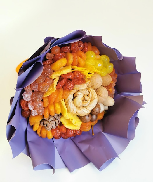 Decorative composition in the form of a bouquet of dried fruits and nuts on a white background