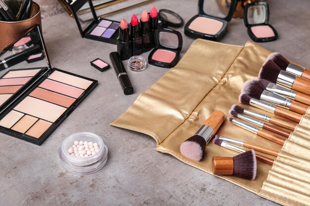 Decorative cosmetics and brushes of professional makeup artist on grey table