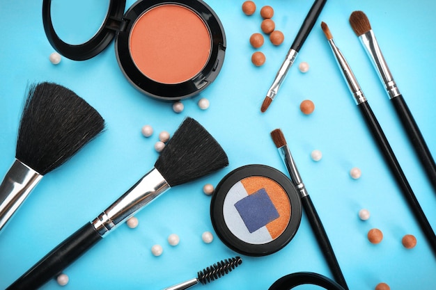 Decorative cosmetics and tools of professional makeup artist on color background