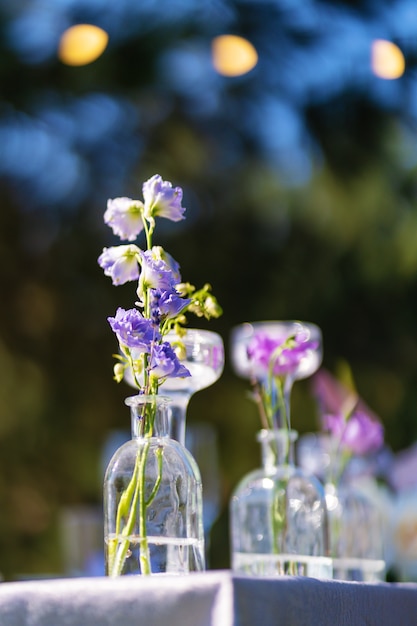 お祝いテーブルの装飾。ガラスの花瓶と新鮮な花。戸外での休日の装飾