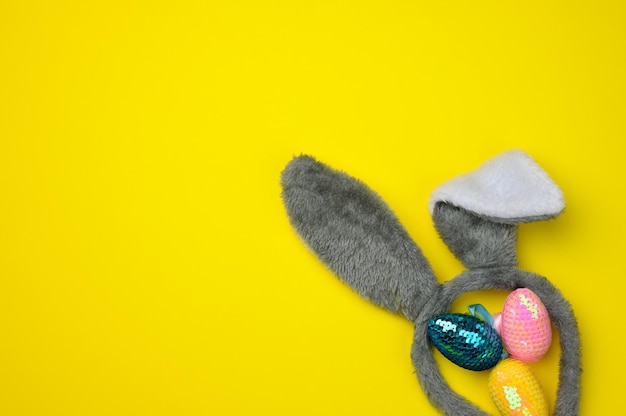 Photo decorative easter eggs and long ears plush bunny toy on a yellow background