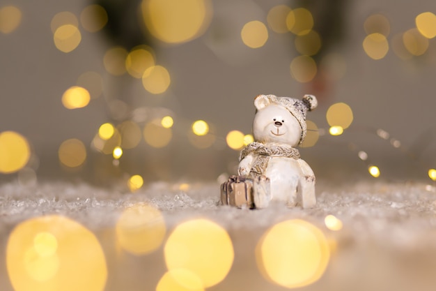 Decorative figurines of a Christmas theme. Statuette of a teddy bear with a scarf, sit next to the box with a Christmas present.