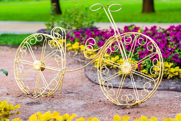 春夏の自然景観デザインで都市公園植物園に咲く色とりどりの花と金属黄色の自転車で装飾的な花壇