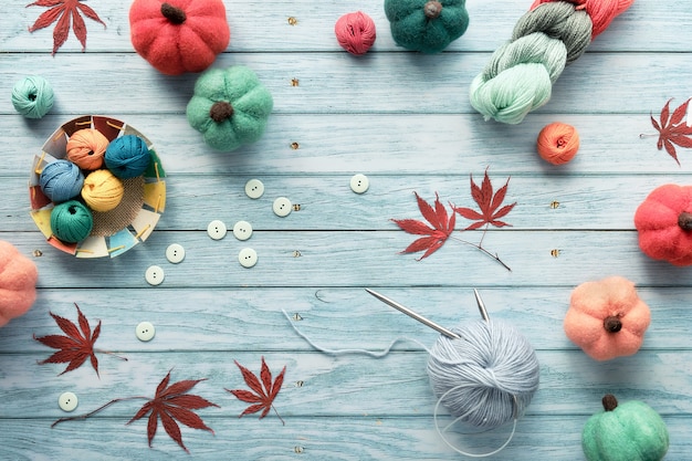 Decorative frame made of wool bundles, yarn balls, decorative felt pumpkins, red maple Autumn leaves.