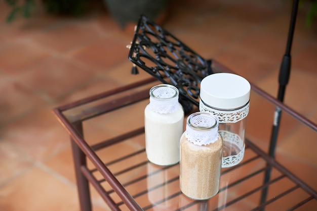 Decorative glass bottles with sand on a glass table