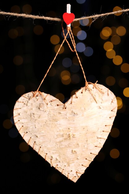 Decorative heart on rope on shiny background