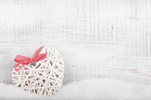 Decorative heart in snow on wooden background