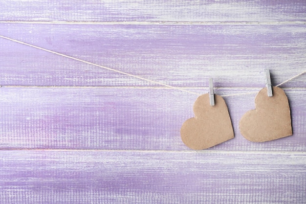 Decorative hearts hanging on clothespins on wooden background