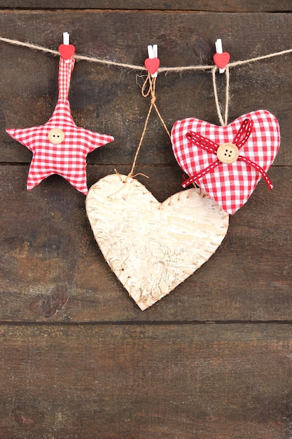 Декоративные сердца и звезда на веревке, на деревянном фоне