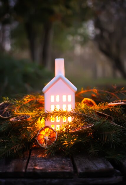 Decorative house lantern with burning candle in autumn park at evening.