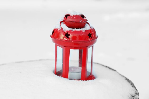 Decorative lantern on wooden stump over snow surface