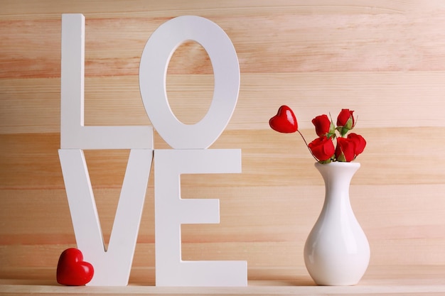 Decorative letters forming word LOVE with flowers on wooden background