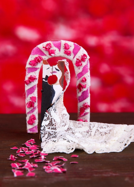 Decorative married loving couple on wooden table on red background