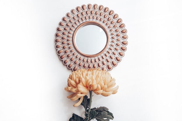 Photo decorative mirror and yellow flower on a white wall. home decor