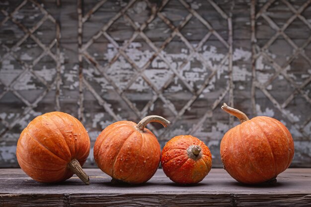 Decorative orange pumpkins on dark wooden table. Old gray table with geometric pattern, 