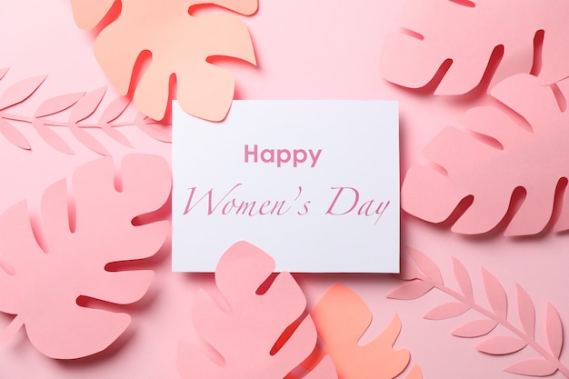 Декоративные пальмовые листья и надпись Happy women day на цвете, вид сверху